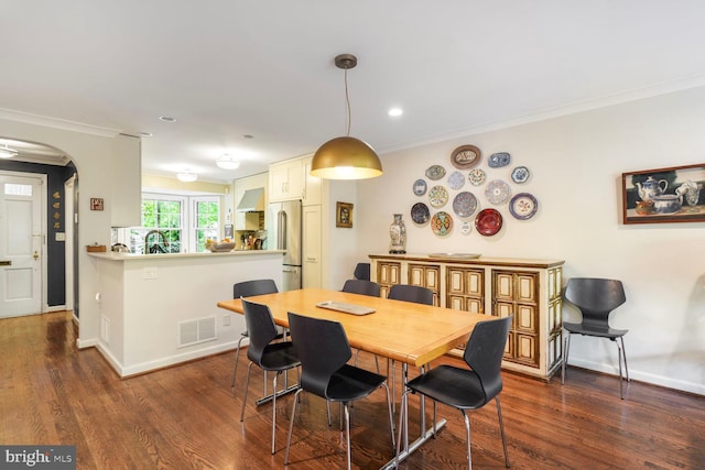 dining area with crown molding, arched walkways, dark wood-type flooring, and visible vents