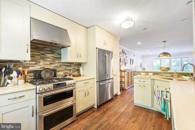 kitchen with tasteful backsplash, a sink, dark wood-style floors, stainless steel appliances, and wall chimney exhaust hood