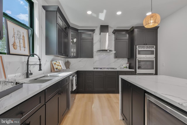 1904 Jackson St NE, Washington, DC 20018 - kitchen featuring wall chimney range hood, appliances with stainless steel finishes, light stone countertops, a sink, and light wood-style flooring