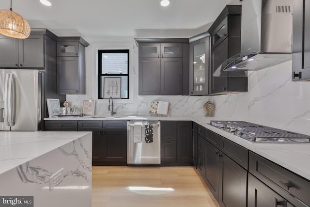 1904 Jackson St NE, Washington, DC 20018 - kitchen with wall chimney range hood, appliances with stainless steel finishes, light stone counters, light wood finished floors, and backsplash
