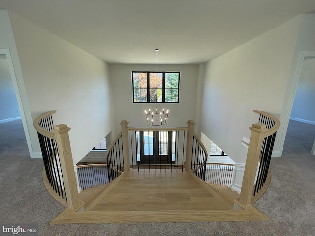 carpeted entryway featuring baseboards and a notable chandelier