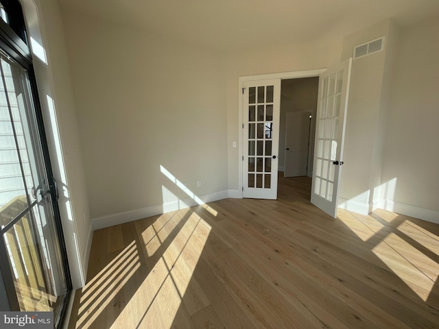 interior space featuring french doors, visible vents, wood finished floors, baseboards, and a wealth of natural light