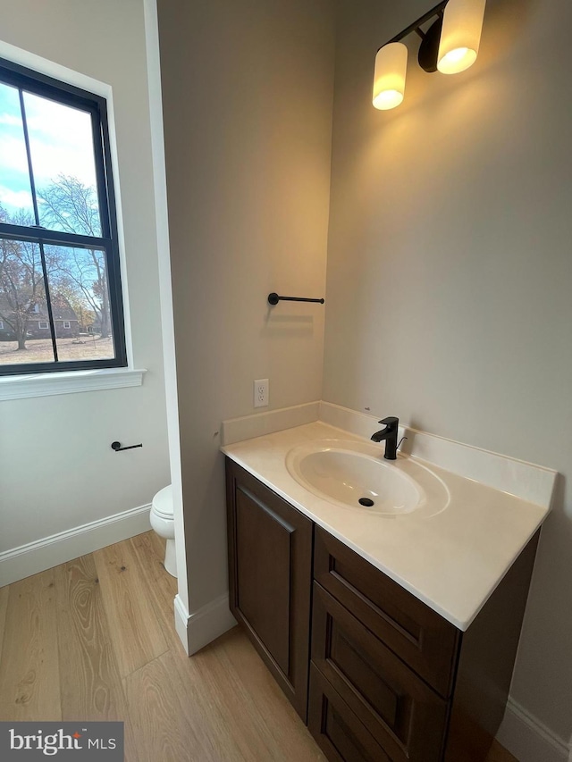 bathroom featuring baseboards, vanity, toilet, and wood finished floors
