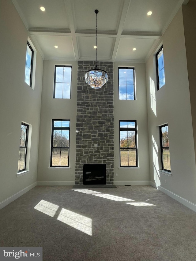 unfurnished living room with carpet flooring, a high ceiling, a notable chandelier, and coffered ceiling