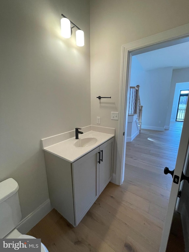 bathroom with toilet, baseboards, wood finished floors, and vanity
