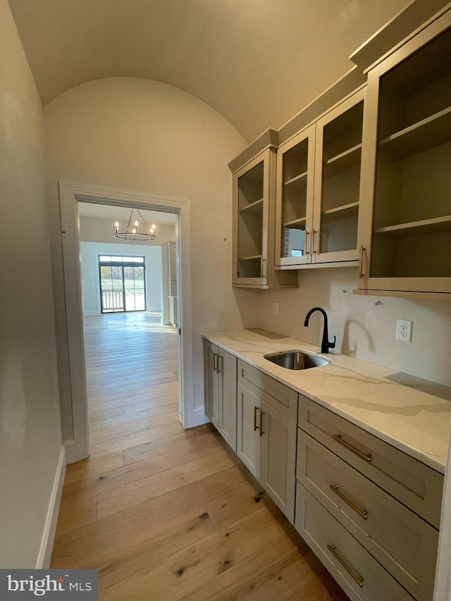kitchen featuring baseboards, a notable chandelier, a sink, and light wood-type flooring