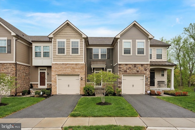 townhome / multi-family property with driveway, a front lawn, stone siding, and a garage