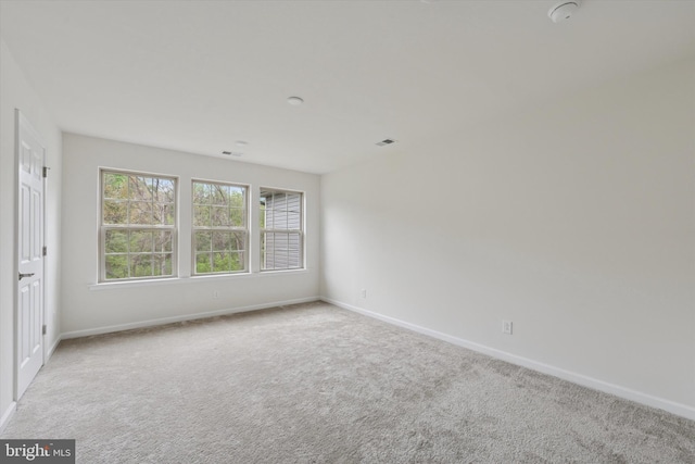 carpeted spare room featuring baseboards and visible vents