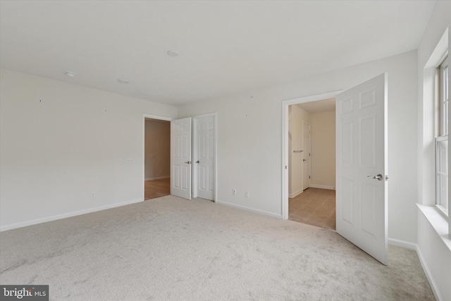 unfurnished bedroom with light colored carpet and baseboards