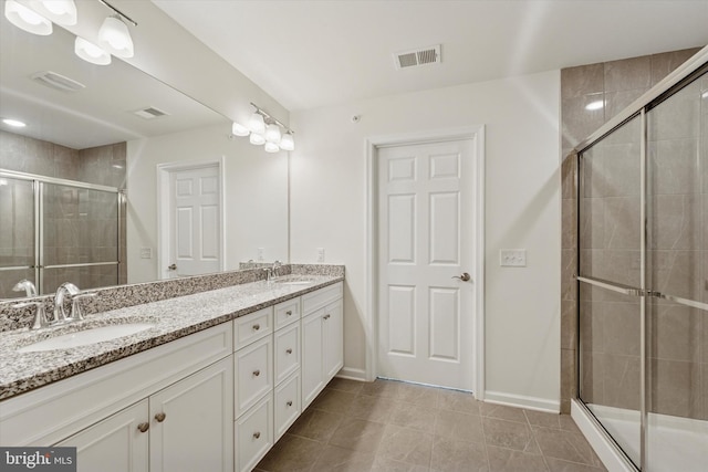 bathroom featuring a sink, a shower stall, double vanity, and visible vents