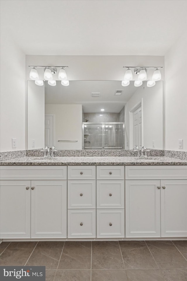 full bathroom featuring double vanity, visible vents, a shower stall, and a sink