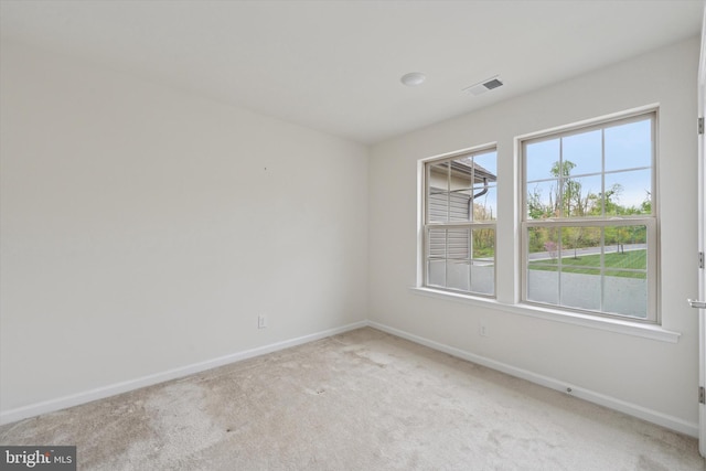 spare room featuring baseboards, light carpet, and visible vents