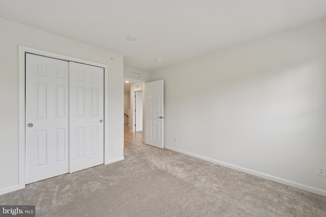 unfurnished bedroom with a closet, carpet, and baseboards