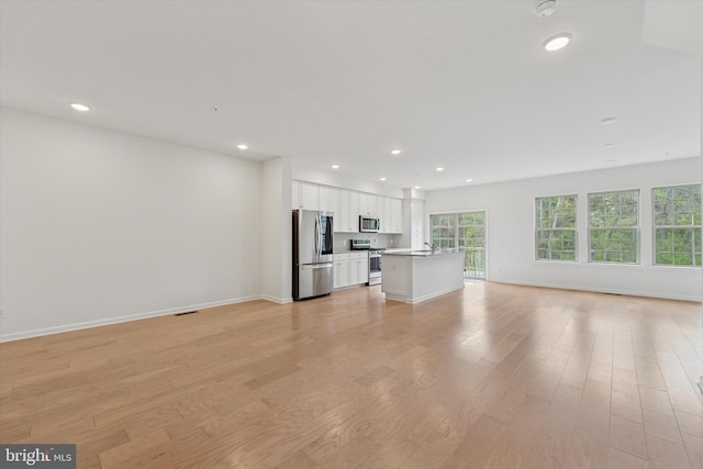 unfurnished living room with recessed lighting, baseboards, and light wood-style flooring