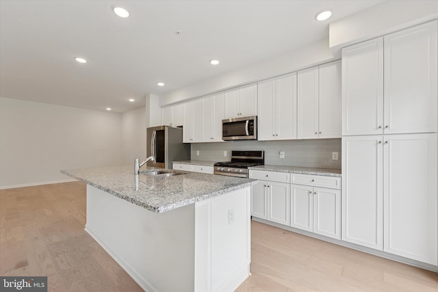 kitchen featuring light wood-style floors, a sink, white cabinetry, and appliances with stainless steel finishes