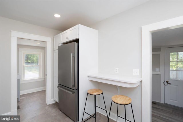 223 Henry St, Cambridge, MD 21613 - kitchen with a kitchen bar, baseboards, white cabinets, freestanding refrigerator, and recessed lighting