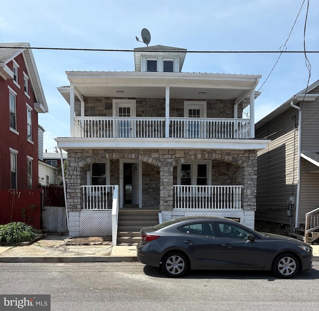 view of front of property featuring covered porch, a balcony, and stone siding