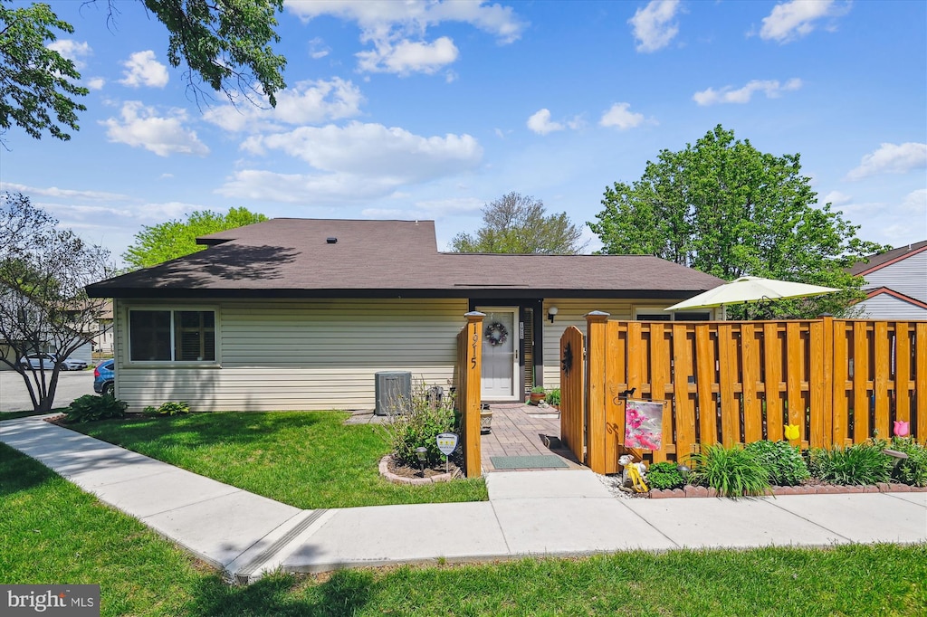view of front of property with central air condition unit, a front lawn, and fence