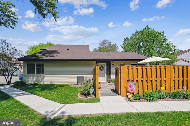 view of front of property with central air condition unit, a front lawn, and fence