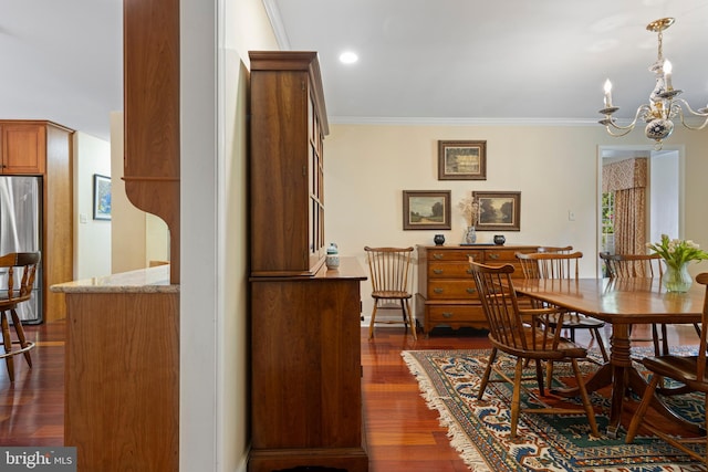 dining area with a chandelier, dark wood finished floors, and crown molding