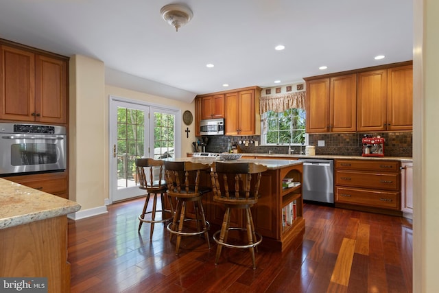 kitchen featuring stainless steel appliances, healthy amount of natural light, brown cabinetry, backsplash, and recessed lighting