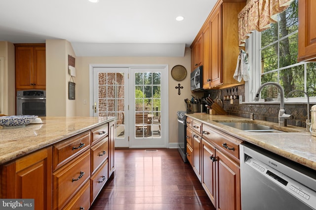 kitchen with stainless steel appliances, a sink, plenty of natural light, light stone countertops, and recessed lighting