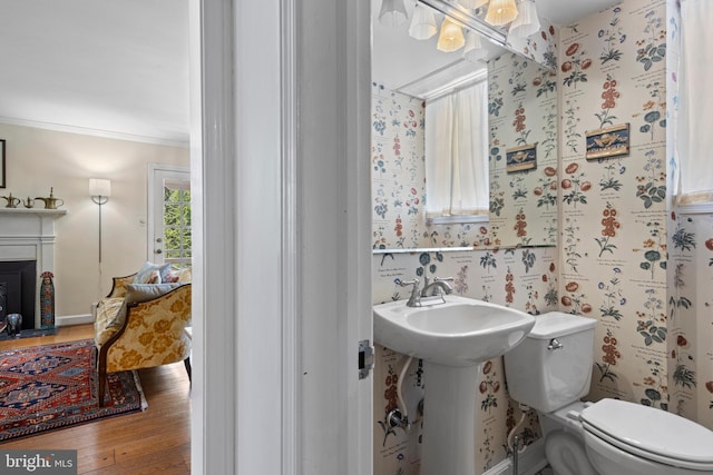 half bathroom featuring hardwood / wood-style floors, toilet, ornamental molding, and wallpapered walls