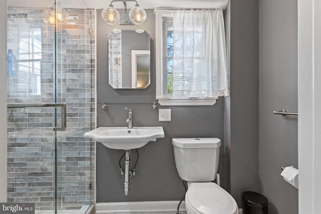 full bathroom with toilet, a shower stall, baseboards, and a sink