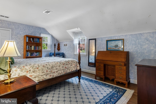 bedroom with wallpapered walls, wood finished floors, lofted ceiling, and baseboards