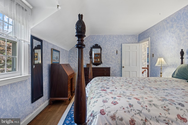 bedroom with wallpapered walls, wood finished floors, and baseboards