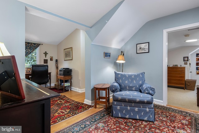 living area featuring vaulted ceiling, wood finished floors, baseboards, and an office area
