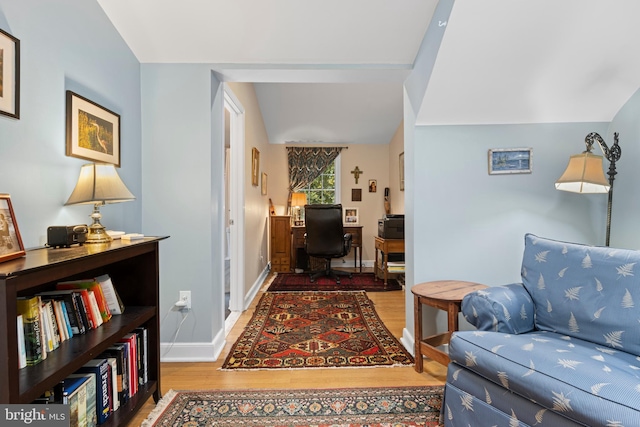 hall featuring wood finished floors, baseboards, and an office area
