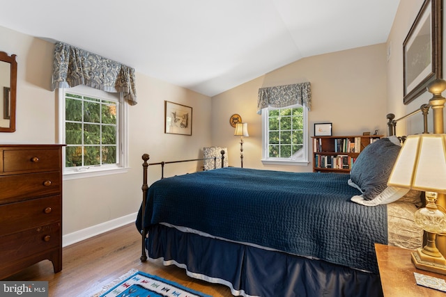 bedroom with wood finished floors, lofted ceiling, and baseboards