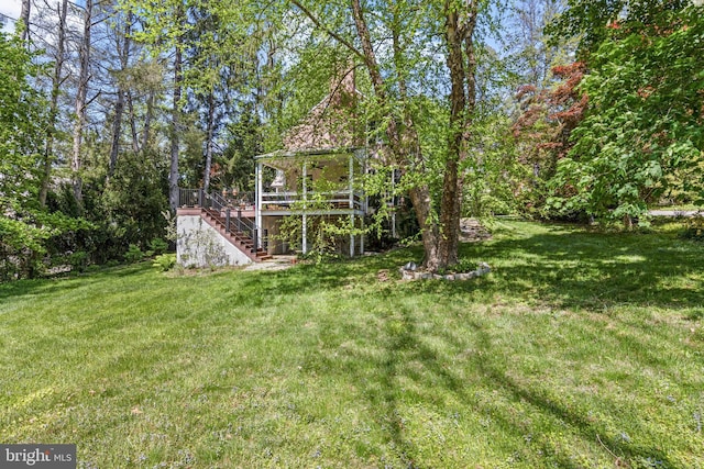 view of green lawn with stairway and a wooden deck