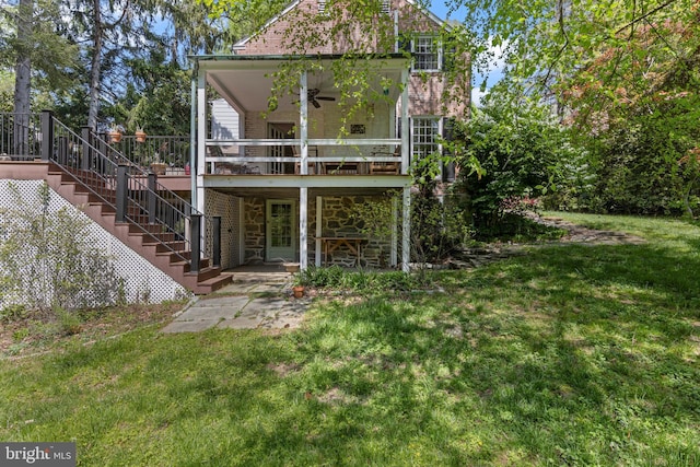 rear view of property with stone siding, stairs, a lawn, a patio, and a deck