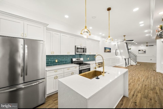 kitchen with light countertops, stainless steel appliances, white cabinetry, decorative backsplash, and a center island with sink