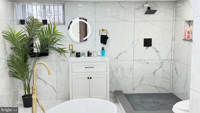 bathroom with tile walls, a marble finish shower, and vanity