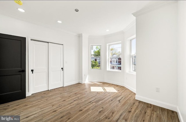 unfurnished bedroom featuring baseboards, ornamental molding, a closet, and wood finished floors