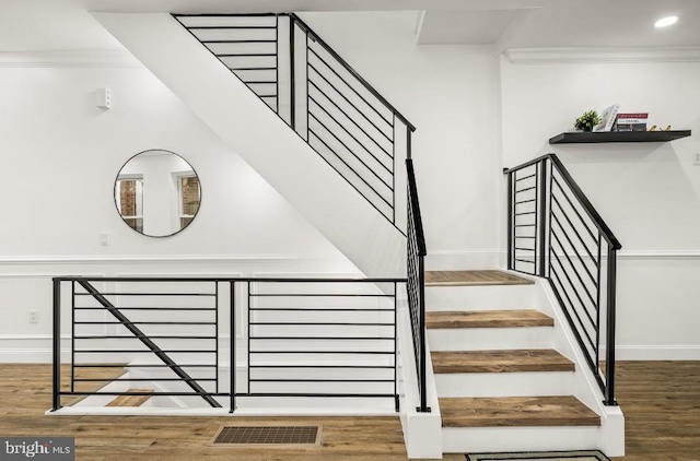 stairway featuring visible vents, crown molding, wood finished floors, baseboards, and recessed lighting
