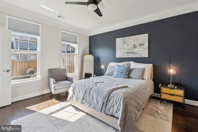 bedroom featuring crown molding, baseboards, wood finished floors, and visible vents