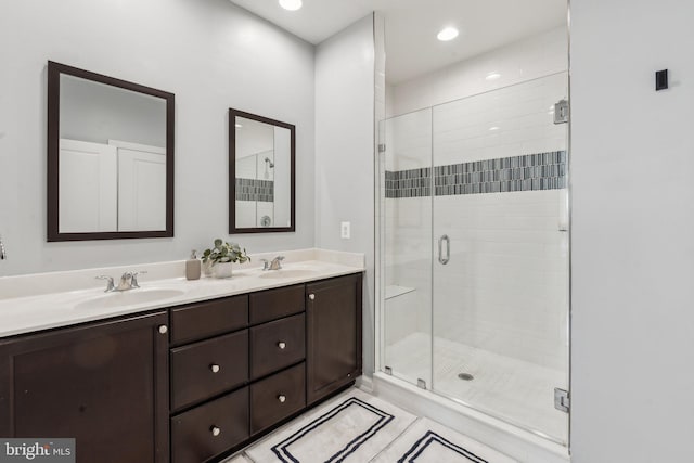 bathroom with double vanity, a sink, a stall shower, and tile patterned flooring