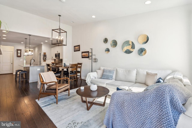 living room with a towering ceiling, baseboards, dark wood-style floors, recessed lighting, and a chandelier