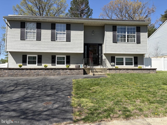 bi-level home featuring fence and a front lawn