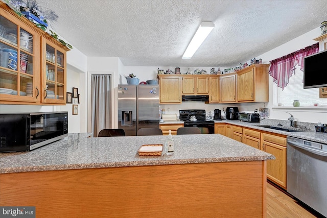 kitchen with a textured ceiling, a sink, extractor fan, black appliances, and light wood-style flooring