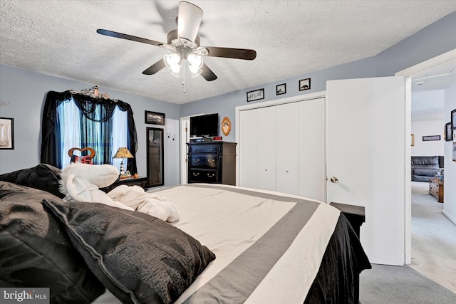 carpeted bedroom with a closet, a ceiling fan, and a textured ceiling