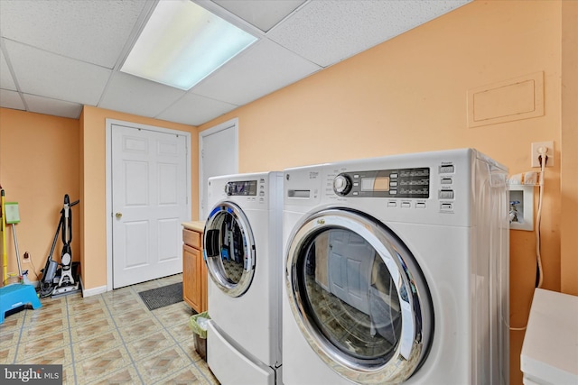 clothes washing area with baseboards, cabinet space, and washer and dryer