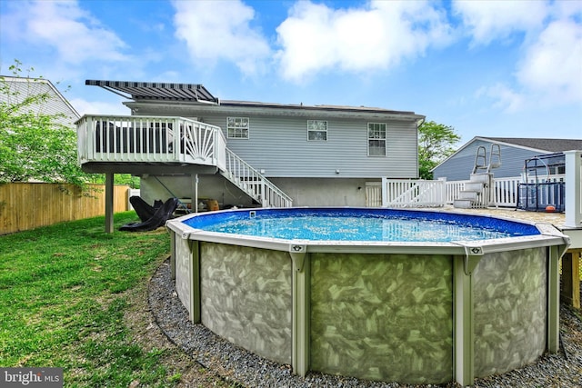 rear view of property with a wooden deck, fence, stairs, a fenced in pool, and a yard