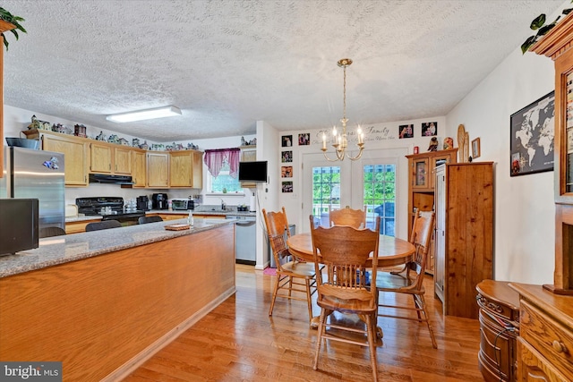 kitchen featuring an inviting chandelier, range hood, light wood-type flooring, a textured ceiling, and stainless steel appliances