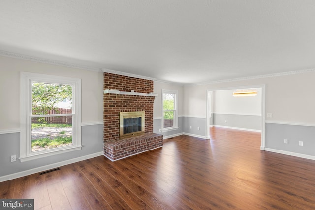 unfurnished living room featuring crown molding, baseboards, a fireplace, and wood finished floors