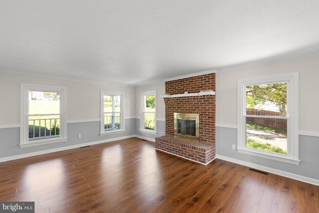 unfurnished living room featuring a brick fireplace, dark wood-style flooring, baseboards, and visible vents